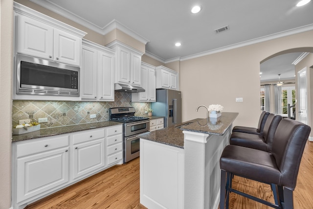 kitchen featuring stainless steel appliances, visible vents, white cabinets, a sink, and under cabinet range hood