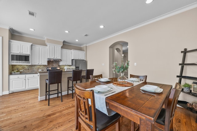 dining room with arched walkways, recessed lighting, visible vents, ornamental molding, and light wood-type flooring