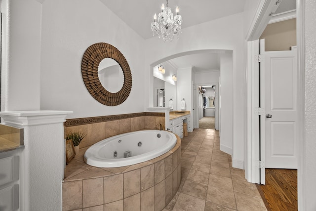 full bathroom featuring ornamental molding, tile patterned floors, a whirlpool tub, vanity, and a notable chandelier