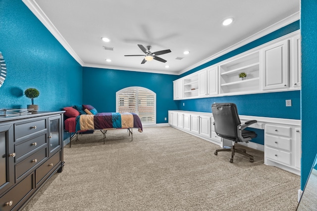 office area featuring light carpet, visible vents, a ceiling fan, built in desk, and crown molding