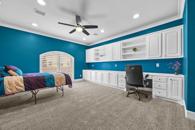 bedroom with ornamental molding, built in study area, visible vents, and light colored carpet