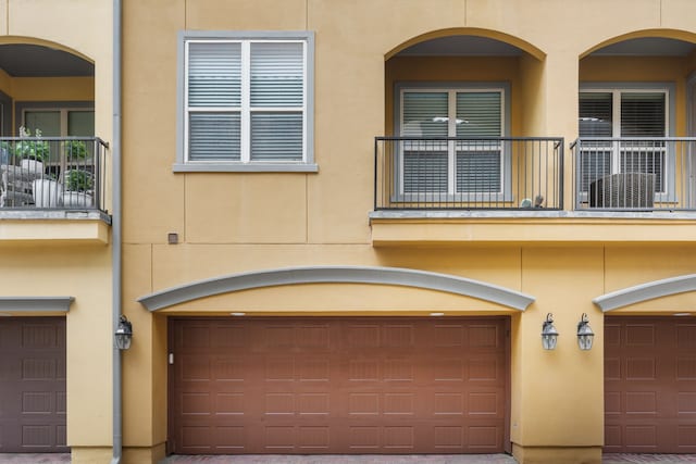 view of front of house featuring an attached garage, a balcony, and stucco siding