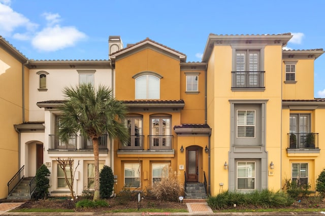 mediterranean / spanish-style home featuring a tile roof, a chimney, and stucco siding