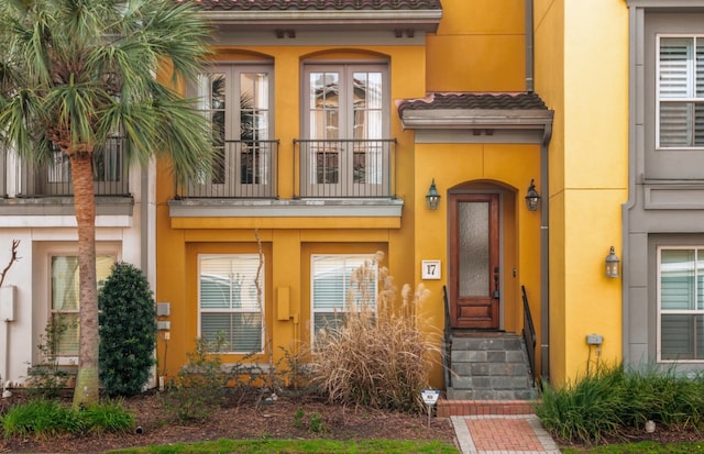 property entrance with a tiled roof, a balcony, and stucco siding