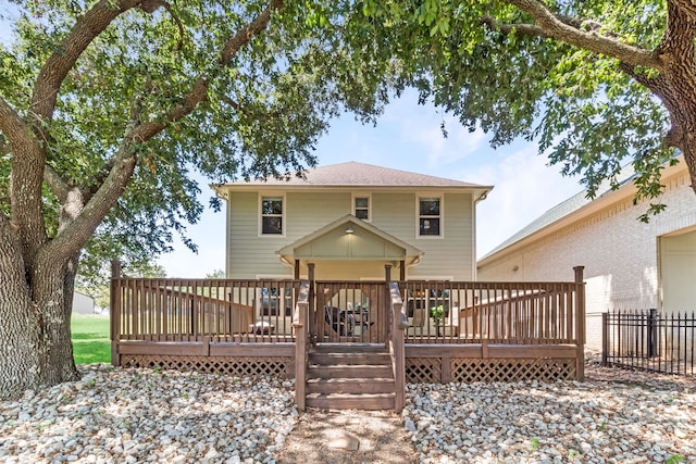 rear view of house with fence and a deck