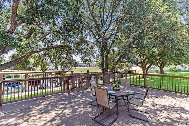 wooden terrace with outdoor dining space and a lawn