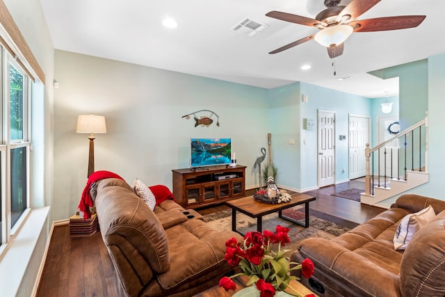 living room featuring visible vents, stairway, baseboards, and wood finished floors