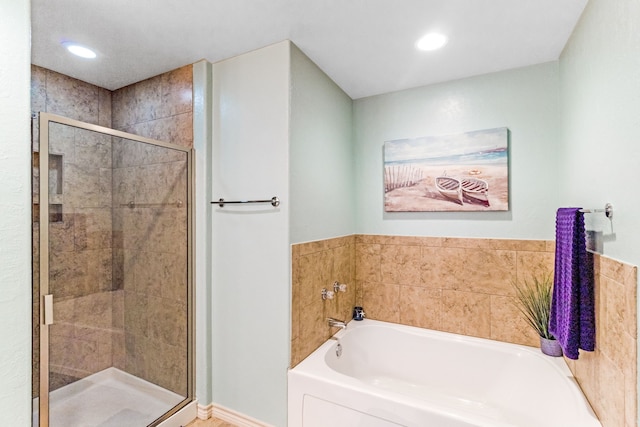 bathroom featuring a stall shower, a bath, and recessed lighting