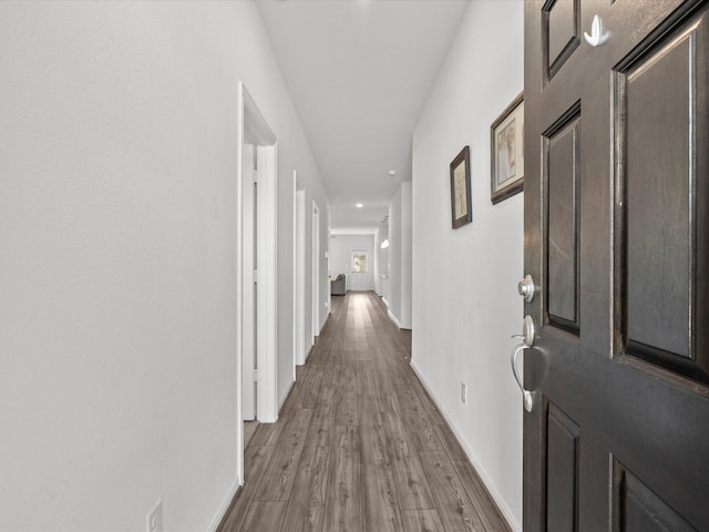 corridor featuring baseboards and wood finished floors