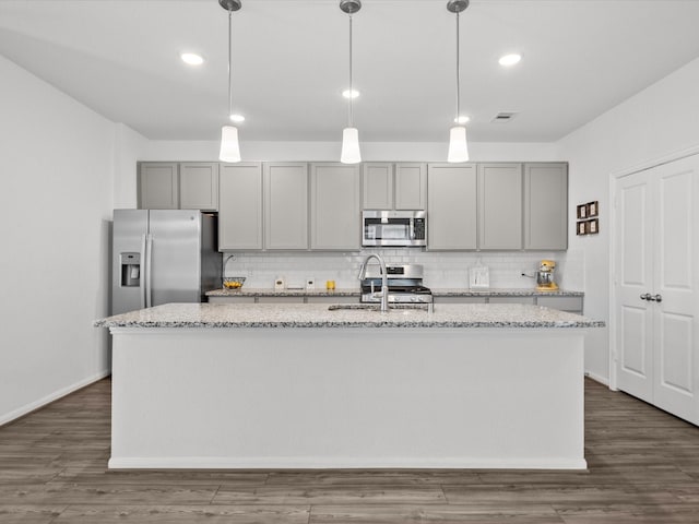 kitchen with appliances with stainless steel finishes, gray cabinets, a sink, and an island with sink