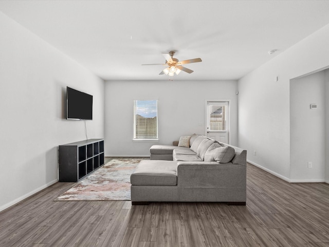 living area featuring a ceiling fan, baseboards, and wood finished floors