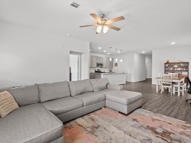 living room with ceiling fan, visible vents, dark wood finished floors, and recessed lighting