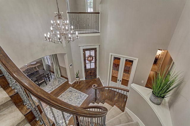 entrance foyer with arched walkways, french doors, stairway, a towering ceiling, and hardwood / wood-style flooring