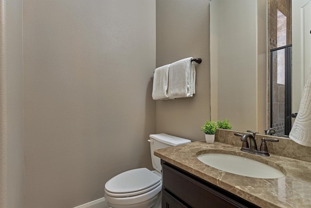 bathroom featuring baseboards, vanity, and toilet