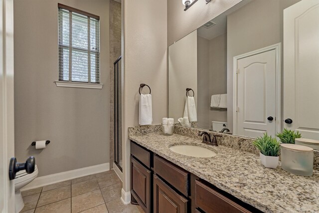 bathroom with a stall shower, vanity, toilet, and tile patterned floors