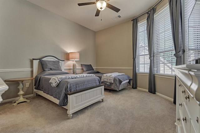 bedroom featuring baseboards, visible vents, a ceiling fan, and light colored carpet