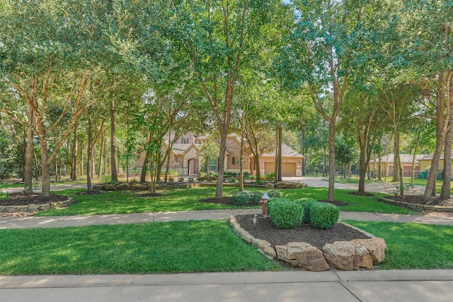 view of property's community with a garage, a yard, and driveway