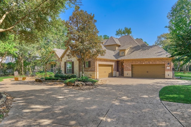 view of front facade with a shingled roof, concrete driveway, stone siding, an attached garage, and brick siding