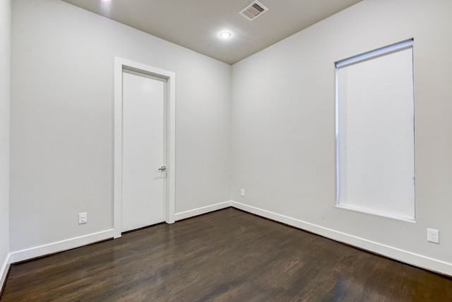 unfurnished room with dark wood-type flooring, visible vents, and baseboards