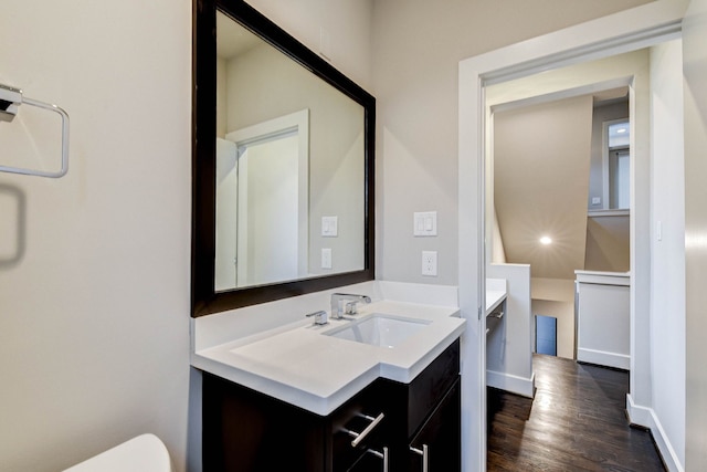 bathroom with toilet, wood finished floors, vanity, and baseboards