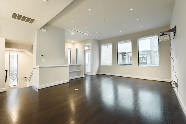 unfurnished room featuring dark wood-style floors, visible vents, and baseboards