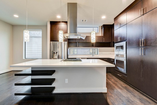 kitchen featuring island exhaust hood, appliances with stainless steel finishes, dark wood-type flooring, a sink, and a kitchen breakfast bar