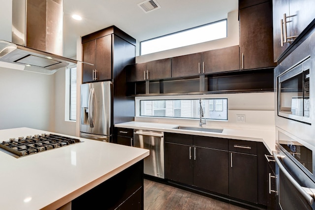 kitchen featuring stainless steel appliances, light countertops, visible vents, a sink, and island range hood