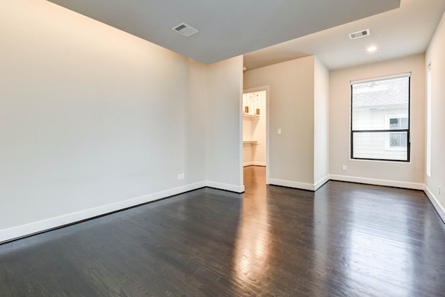 spare room with baseboards, visible vents, dark wood finished floors, and recessed lighting