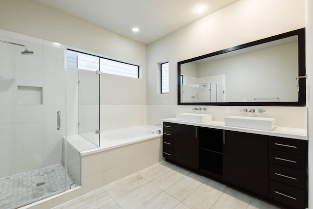 full bathroom with a bath, a stall shower, double vanity, and a sink