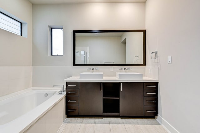 full bath featuring double vanity, a garden tub, baseboards, and a sink