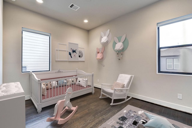 bedroom featuring baseboards, visible vents, multiple windows, and wood finished floors