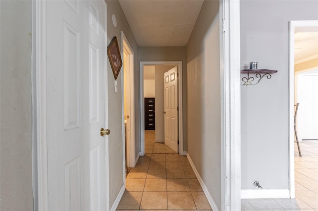 corridor featuring light tile patterned floors and baseboards