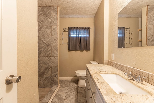 bathroom with toilet, a textured ceiling, tiled shower, and vanity