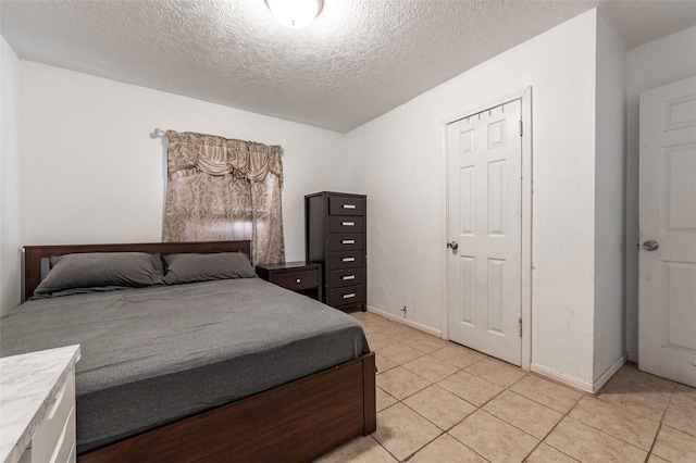 bedroom featuring light tile patterned floors, a textured ceiling, and baseboards