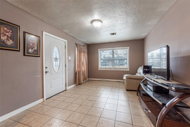 foyer with light tile patterned floors, a textured ceiling, visible vents, and baseboards