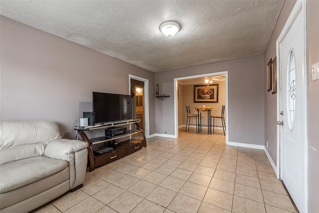 living area featuring a textured ceiling, baseboards, and light tile patterned floors