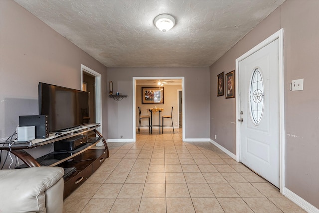 entryway featuring light tile patterned floors, baseboards, and a textured ceiling