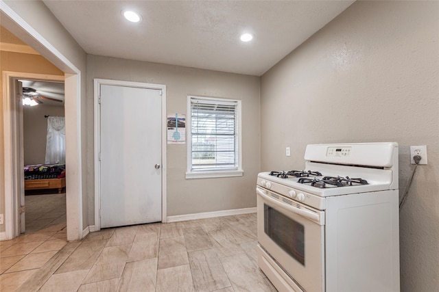 kitchen with recessed lighting, baseboards, and white gas range