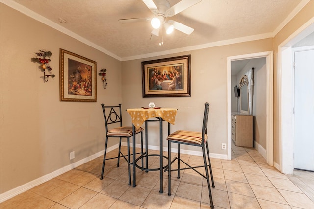 dining area with light tile patterned floors, a textured ceiling, a ceiling fan, baseboards, and crown molding