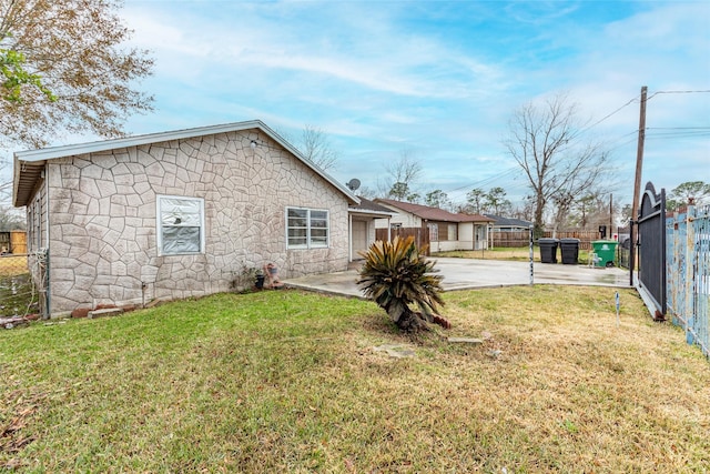 exterior space with stone siding, fence, and a lawn