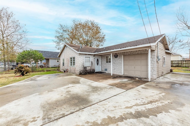 ranch-style house with concrete driveway, stone siding, an attached garage, and fence