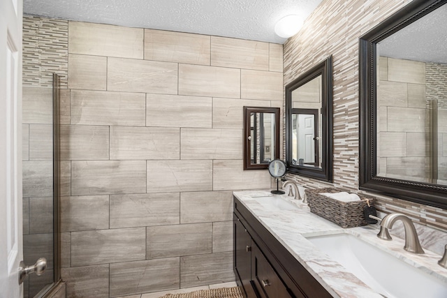 bathroom with double vanity, a textured ceiling, and a sink