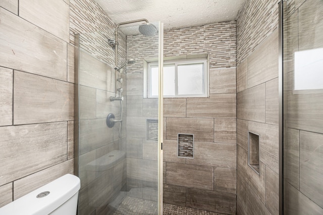 full bath with a textured ceiling, a stall shower, and toilet