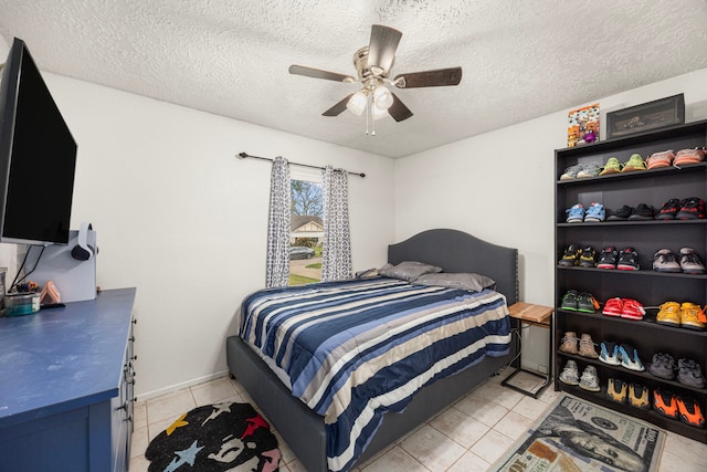 bedroom featuring light tile patterned floors, ceiling fan, and a textured ceiling