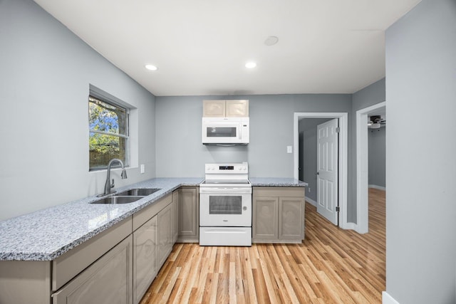 kitchen with white appliances, light wood-type flooring, a sink, and recessed lighting