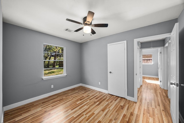 unfurnished bedroom with attic access, light wood-type flooring, visible vents, and baseboards