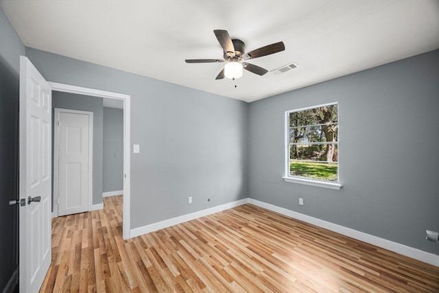 unfurnished room featuring light wood-style floors, baseboards, visible vents, and a ceiling fan