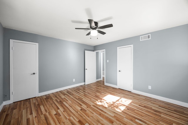 unfurnished bedroom featuring baseboards, visible vents, ceiling fan, and wood finished floors