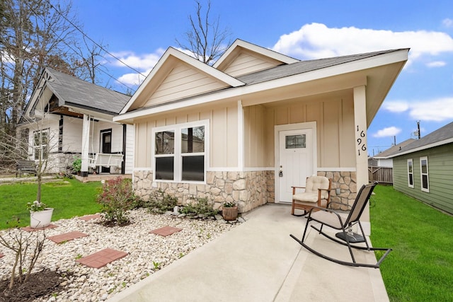 exterior space featuring stone siding, a porch, board and batten siding, and a front yard