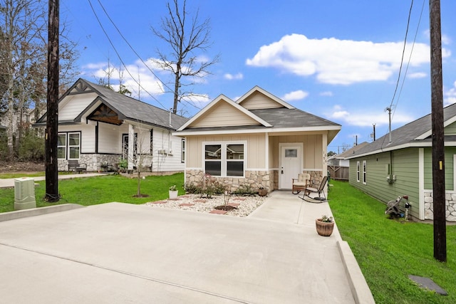 view of front of property featuring stone siding, a front lawn, and board and batten siding